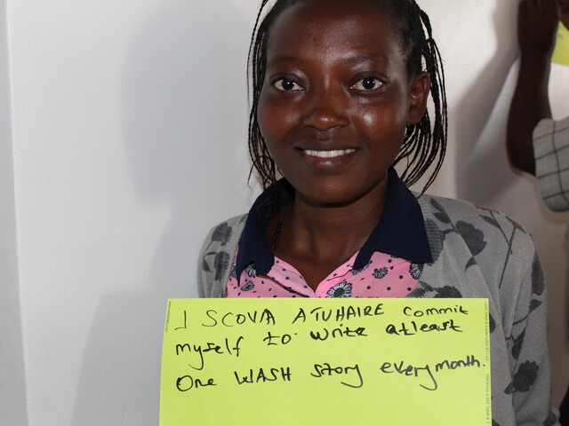 A journalists holds up a placard stating her commitment to WASH coverage