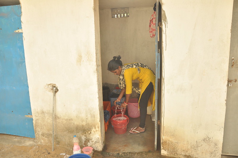Woman cleaning toilet, Odisha, India