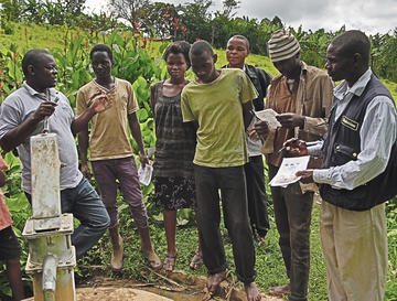 Martin Watsisi, left, talks to community members at Magura shallow well in Karambi sub-county, Kabarole District.